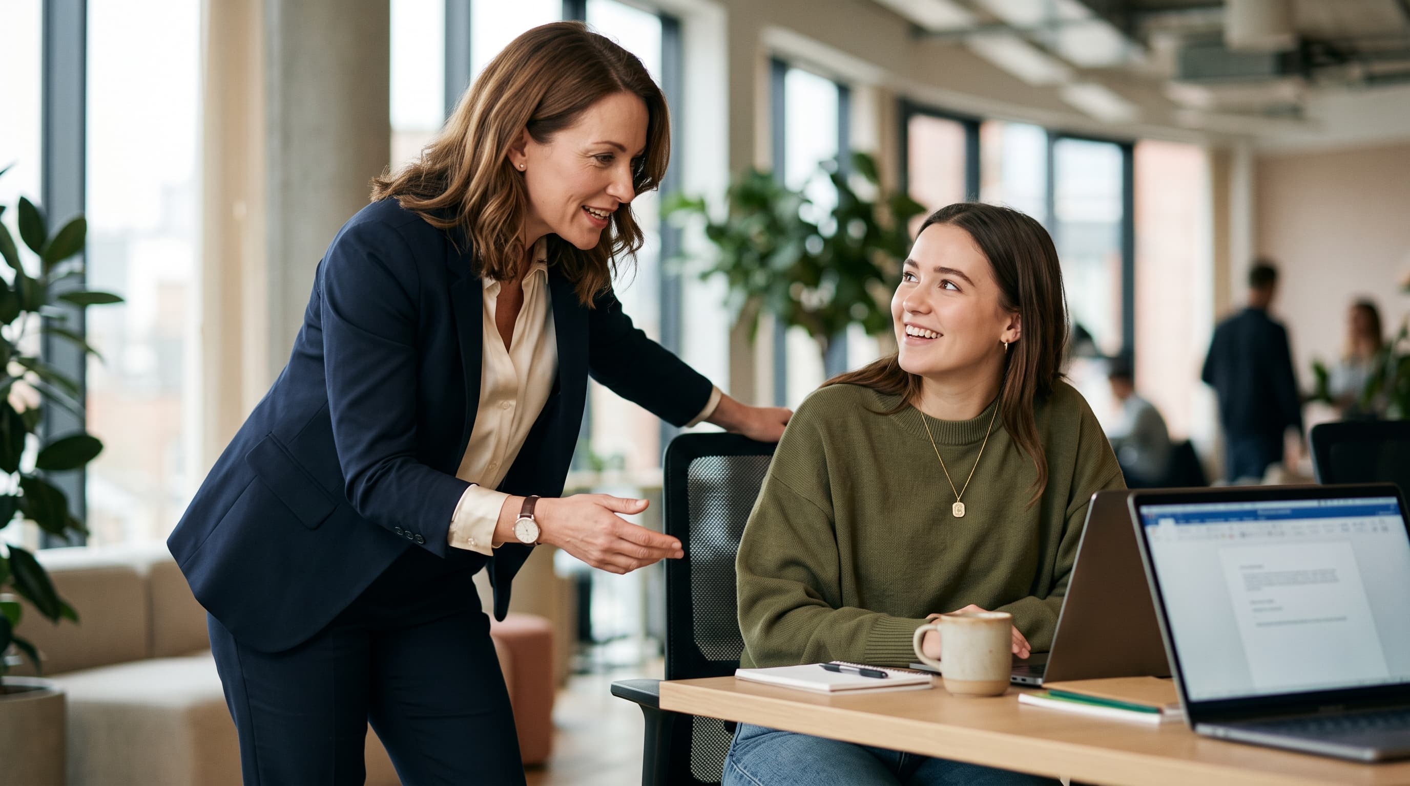 Two business professionals reviewing a laptop and planning documents in a sunlit office
